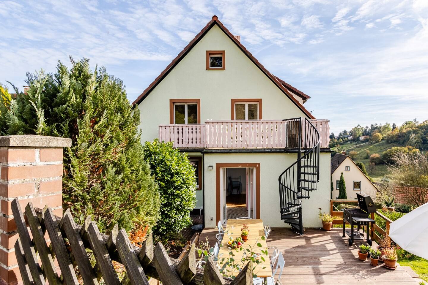 Rückseite des Burgi mit Holzterrasse, Wendeltreppe und rosa Balkon
