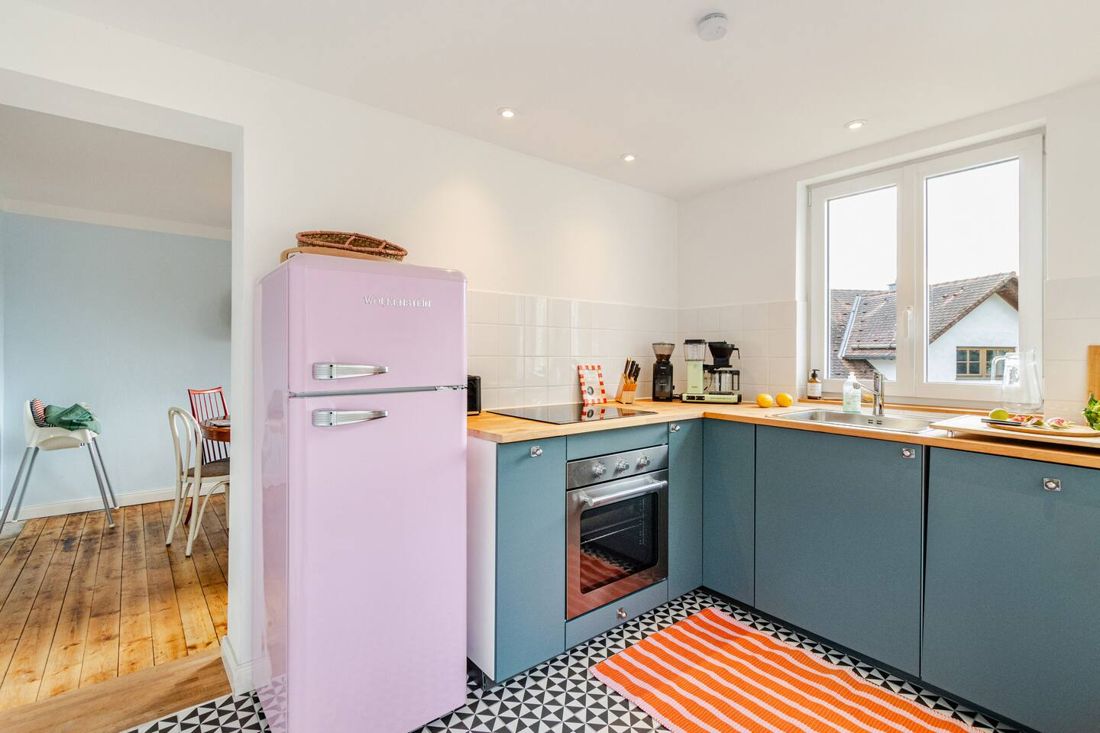Küche mit rosa Kühlschrank und orangem Teppich