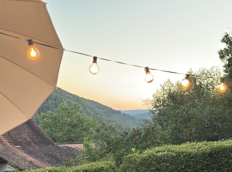 Lichterkette über der Terrasse im Abendlicht mit Blick ins Neckartal
