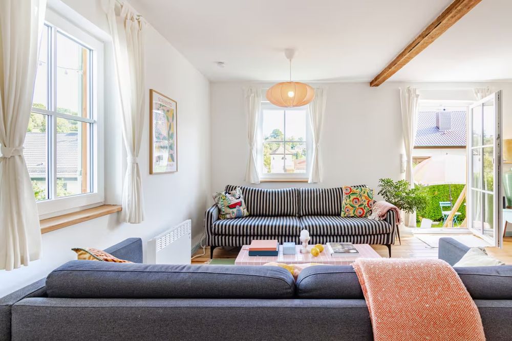 Sofa mit gestreiftem Bezug, Plaid und Fenster zum Garten
