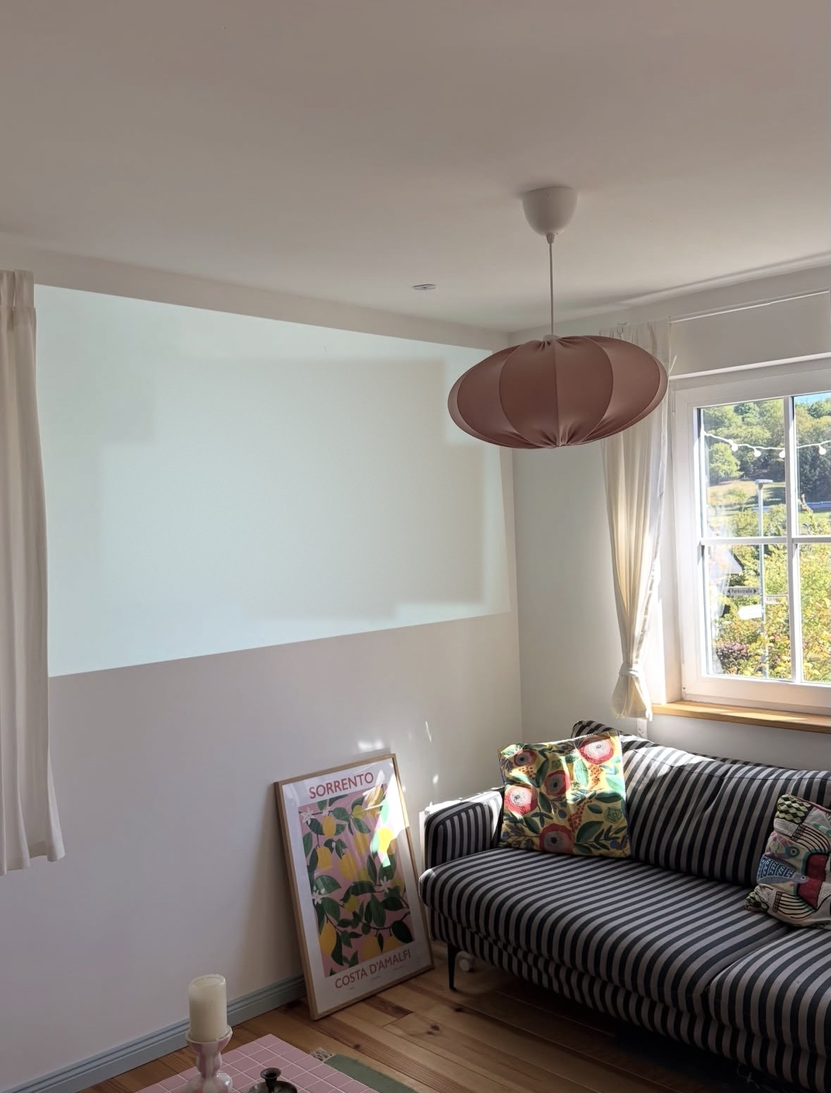 Helle Projektionsfläche an der Wand im Wohnzimmer neben dem Sofa