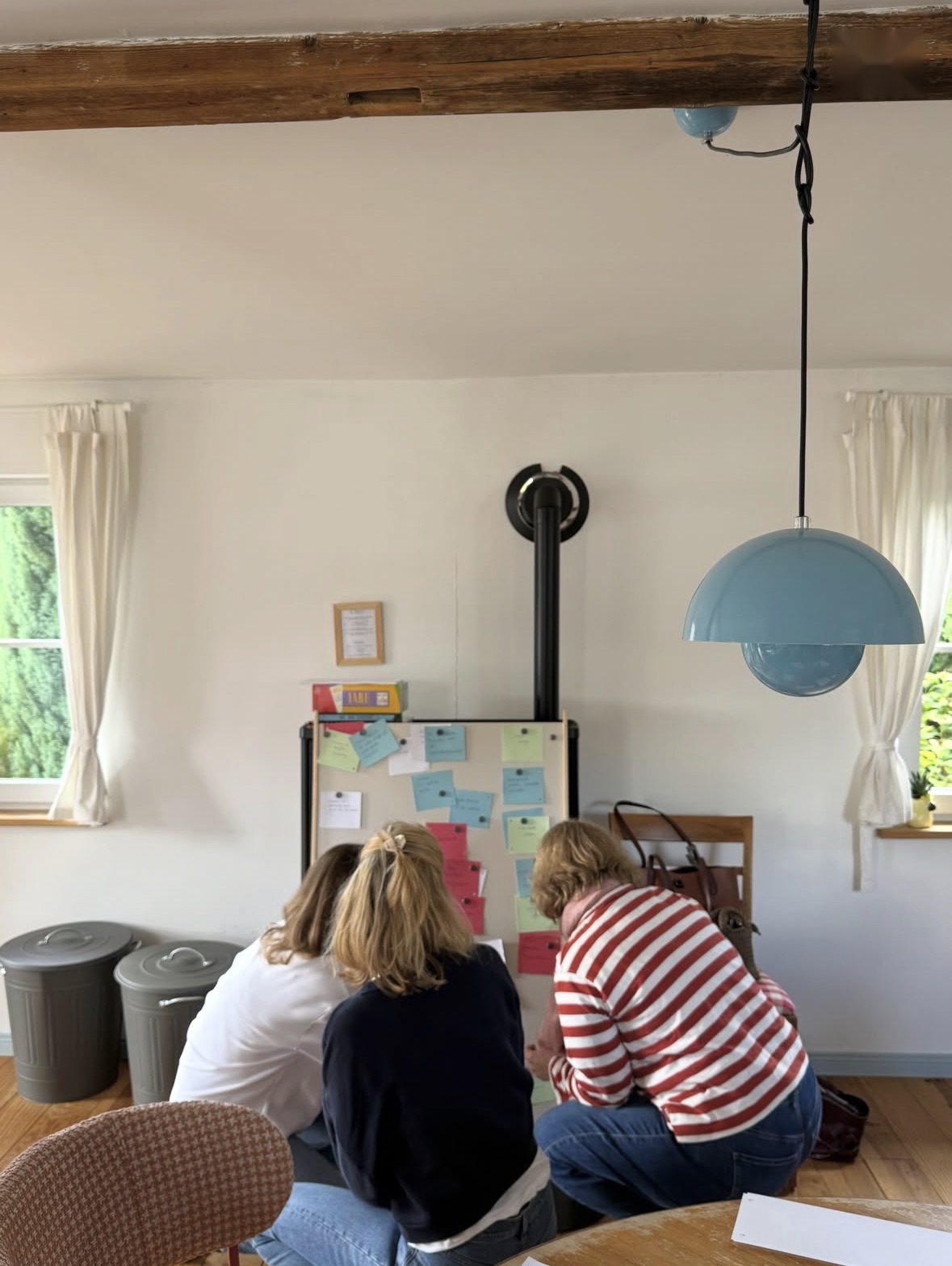 Teilnehmerinnen arbeiten mit bunten Karten an einem Flipchart im hellen Wohnraum