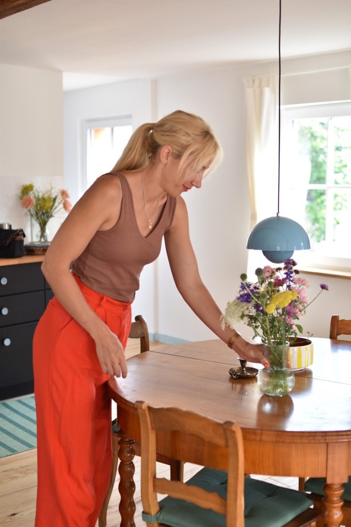 Zita deckt den Tisch im Feni und stellt Blumen darauf